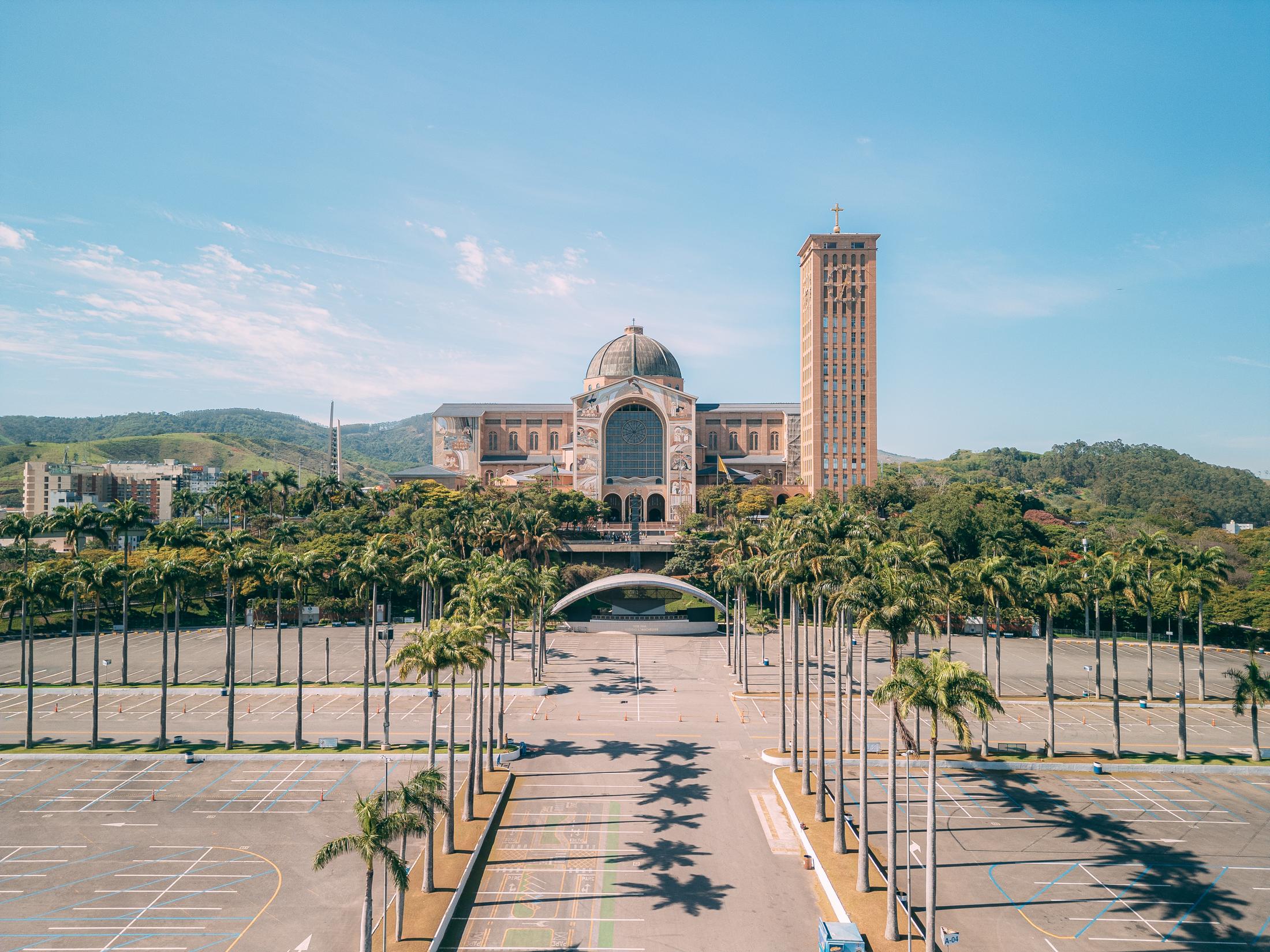 Vista frontal da Basílica Nacional de Aparecida, com o estacionamento arborizado em primeiro plano